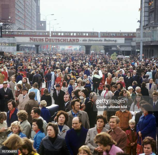 Eine Menschenmenge am Alexanderplatz in Berlin mit Blick in die rathausstraße, im Hintergrund die Hochbahn mit S-Bahn und der Werbung für die...