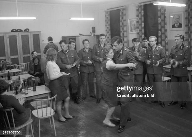 Grenzsoldaten der DDR-Grenztruppen der Nationalen Volksarmee der DDR tanzen bei einer Feier in der Einheit in Motzlar in Thüringen mit weiblichen...