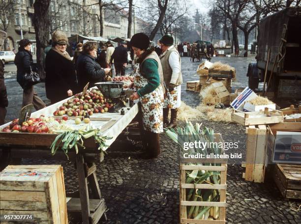 An einem Stand am Wochenmarkt in Berlin-Pankow bietet ein privater Händler Äpfel und Porreestangen an, undatiertes Foto von 1979.