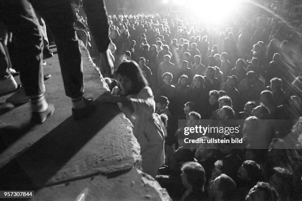 Einen Tag nach der Grenzöffnung in Berlin feiern tausende Menschen auf, vor und hinter der Berliner Mauer am Brandenburger Tor, aufgenommen am . Die...