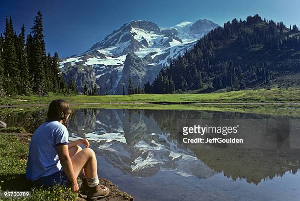 young female hiker at aurora lake with mt rainier reflection - jeff goulden stock pictures, royalty-free photos & images