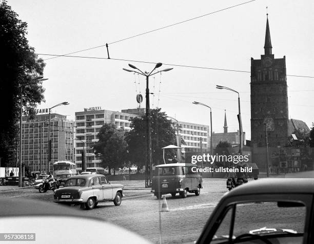 Reger Verkehr herrscht im Sommer 1968 auf dem Schröderplatz an der Langen Straße vor dem Kröpeliner Tor in Rostock. Im Hintergrund das Interhotel...