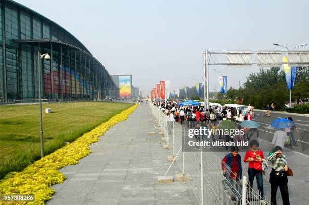 Touristen passieren das Nationale Hallenstadion, in dem zwei Wettkampfstätten unter einem Dach vereinigt sind und das auf dem Olympiagelände "Olympic...