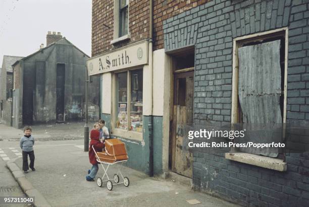 View of young children playing outside a corner shop selling sweets and confectionery in the predominantly republican Falls Road area of west...