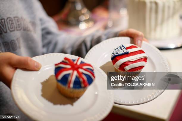 Member of staff at the Hummingbird Bakery poses with cupcakes themed with icing depicting the Union Flag and the US flag to mark the upcoming Royal...