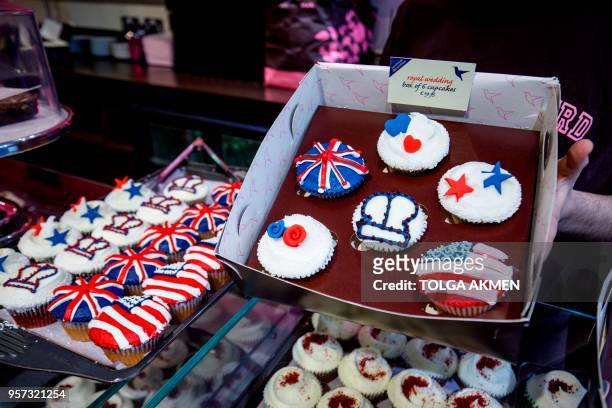 Member of staff at the Hummingbird Bakery poses with cupcakes themed with icing depicting the Union Flag, the US flag, stars, hearts and crowns to...