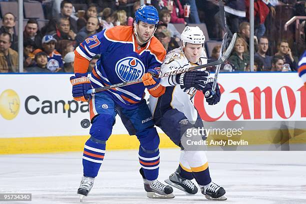 Dustin Penner of the Edmonton Oilers and Wade Belak of the Nashville Predators try to knock down the flying puck at Rexall Place on January 12, 2010...