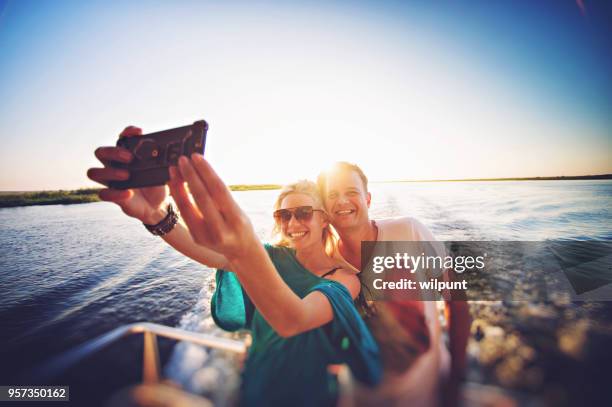 couple taking selfie on back of a safari boat - chobe national park stock pictures, royalty-free photos & images