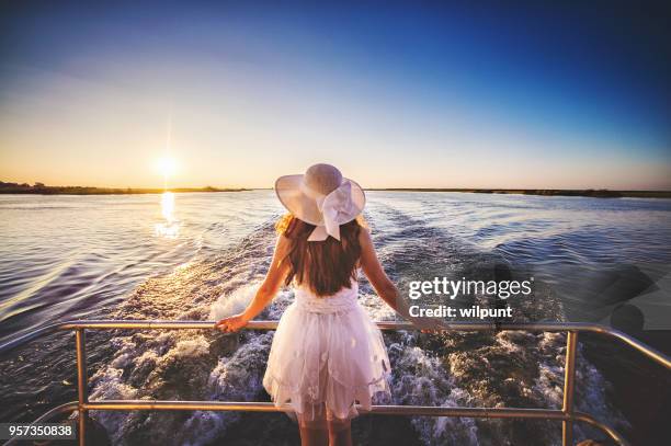 hinteren winkel ansicht weiblich auf der rückseite von einem fahrenden boot bei sonnenuntergang - hochzeit schiff reling stock-fotos und bilder