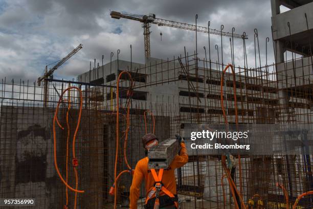 Contractor carries steel rods in front of mesh reinforcement panels during construction at the Reserva Paulista residential complex in Sao Paulo,...