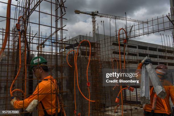 Contractor carries steel rods in front of mesh reinforcement panels at the Reserva Paulista residential complex under construction in Sao Paulo,...