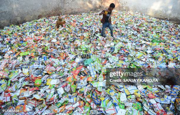 An Indian boy searches for remain food in polythene packets at roadside in Allahabad on May 11, 2018.