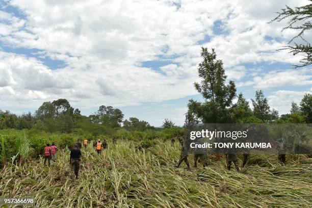 Kenya Defence Force soldiers patrol and inspect in a crop field on May 11, 2018 in search of bodies of victims after a dam burst its banks, sending...