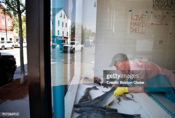 Michael Moynihan, of Cambridge, places a fish in the window of New Deal Fish Market along Cambridge Street in East Cambridge, MA on May 10, 2018. A...