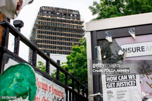 The burned-out shell of Grenfell Tower is seen in west London on May 11, 2018 behind a poster advertising a Justice4Grenfell public meeting that...