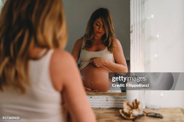 pregnant young adult woman at home - stretch mark stock pictures, royalty-free photos & images