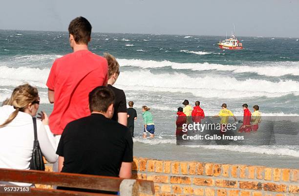 Onlookers watch as the search continues for the body of an unknown foreign man who was torn apart by a Great White shark, after taking a swim in the...