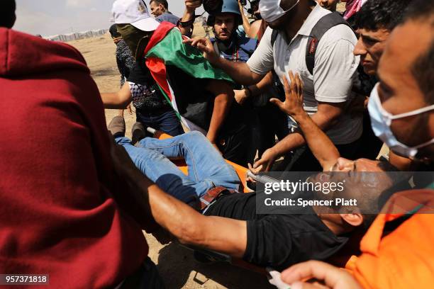 Palestinian man who was shot is rushed to an ambulance during clashes at the border fence with Israel as mass demonstrations at the fence continue on...