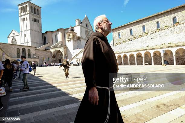 Franciscan monk walks in front of the Basilica Superiore and the Basilica Inferiore of St Francis of Assisi, in Assisi, on May 11, 2018. - German...