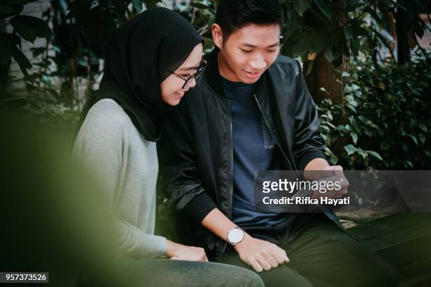 asian couple looking at phone together - smiley face stock pictures, royalty-free photos & images