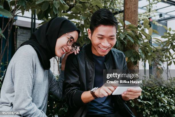 young couple looking at phone - smiley face stock pictures, royalty-free photos & images