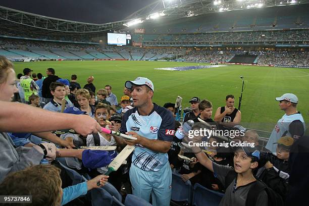 Phil Jaques signs bats during rain break at the Twenty20 Big Bash match between the New South Wales Blues and the Queensland Bulls at ANZ Stadium on...