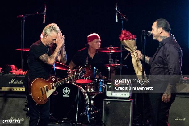 Guitarist Mike McCready receives roses from singer and guitarist Mike Ness while drummer Chad Smith looks on during the MusiCares Concert for...