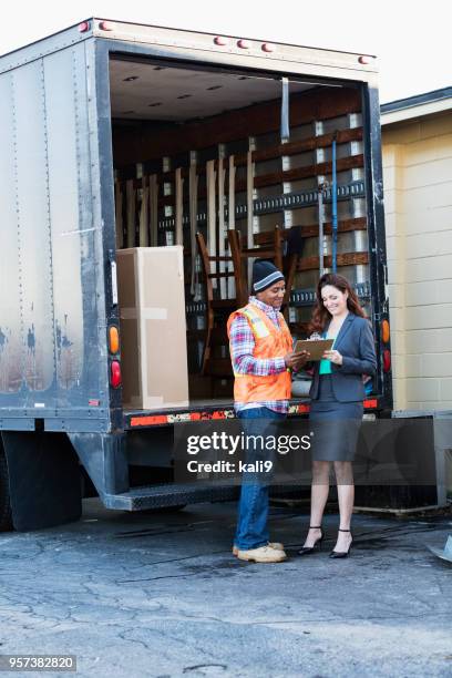 businesswoman receiving delivery, signing a clipboard - loader reading stock pictures, royalty-free photos & images