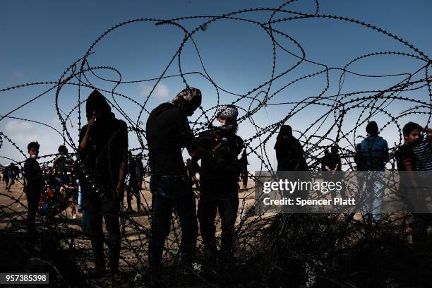 Palestinian youth pull away a section of the border fence with Israel as mass demonstrations at the fence continue on May 11, 2018 in Gaza City,...