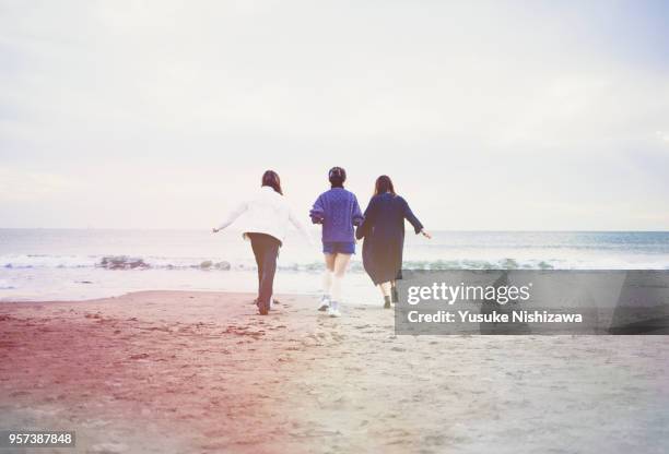 three young women walking together on sandy beach - young teen girl beach ストックフォトと画像