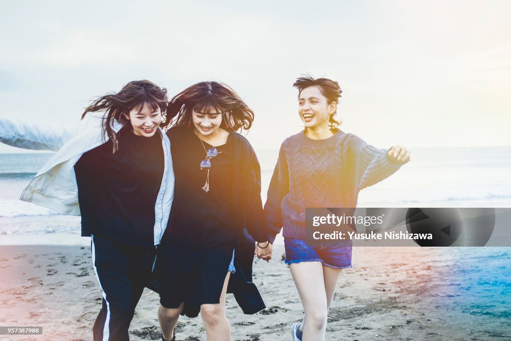 Three young women walking together on sandy beach