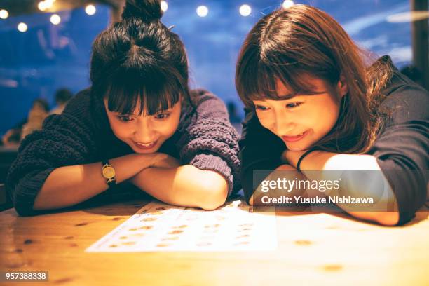 two young women watch a meal menu - girls chatting cafe stock pictures, royalty-free photos & images