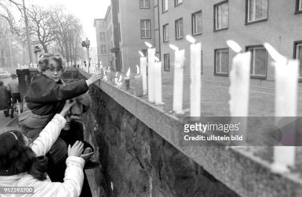 Passanten stellen an einer Mauer an der Bezirksverwaltung Dresden des Ministeriums für Staatssicherheit Kerzen auf, aufgenommen am . Später am Tag...