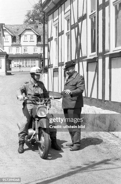 Ein DDR-Grenzer der NVA auf einem Motorrad unterhält sich mit einem Förster im DDR-Grenzort Schierke im Harz, aufgenommen im Juli 1976. Die...