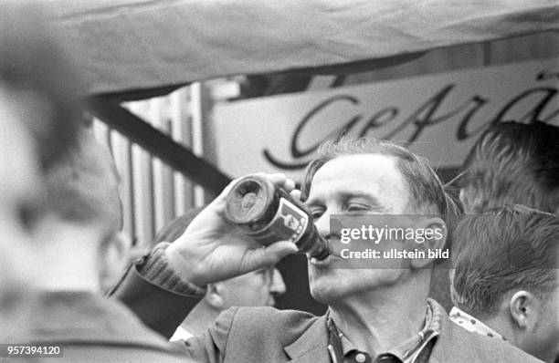 Ein Mann trinkt aus einer Flasche Vollbier bei einem Volksfest zum 1. Mai 1963 in Berlin . Nach der obligatorischen Demonstration zum Kampftag der...