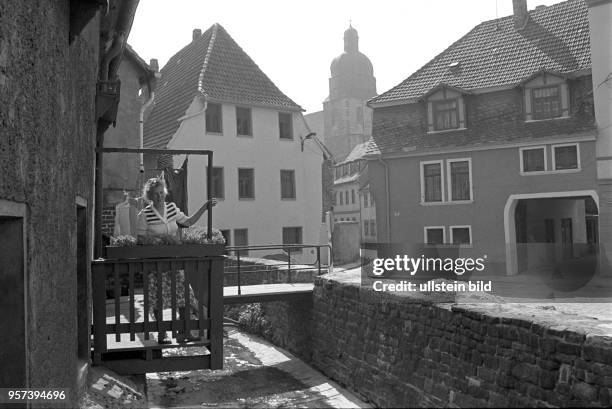 Eine Frau auf einem kleinen Balkon an einem sanierten Haus in den rekonstruierten Altbauten an der "Bösen Sieben", einem kleinen Fluß in der...