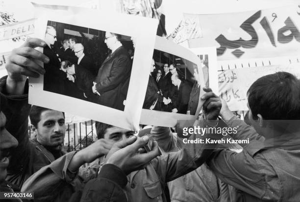 Demonstrators burn pictures of the Shah of Iran with matches while holding them up outside the American Embassy which is occupied by 'students...