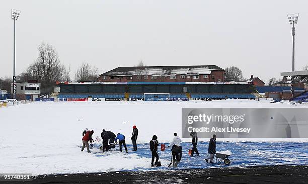 Volunteers help clear snow from the pitch at Macclesfield Town Football Club on January 13, 2010 in Macclesfield, United Kingdom. Macclesfield Town...