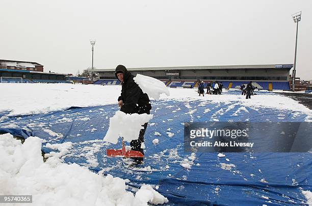 Volunteers help clear snow from the pitch at Macclesfield Town Football Club on January 13, 2010 in Macclesfield, United Kingdom. Macclesfield Town...