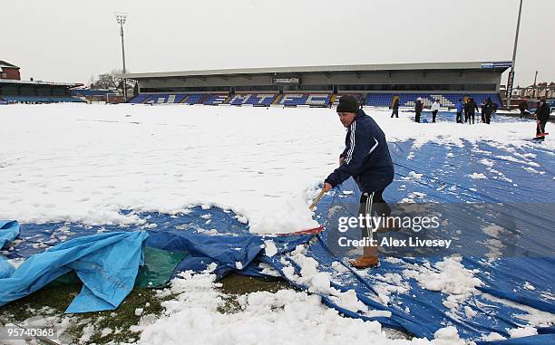 Volunteers help clear snow from the pitch at Macclesfield Town Football Club on January 13, 2010 in Macclesfield, United Kingdom. Macclesfield Town...