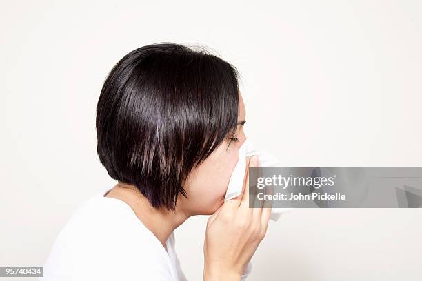 hispanic girl sneezing onto a tissue - closeup of a hispanic woman sneezing foto e immagini stock