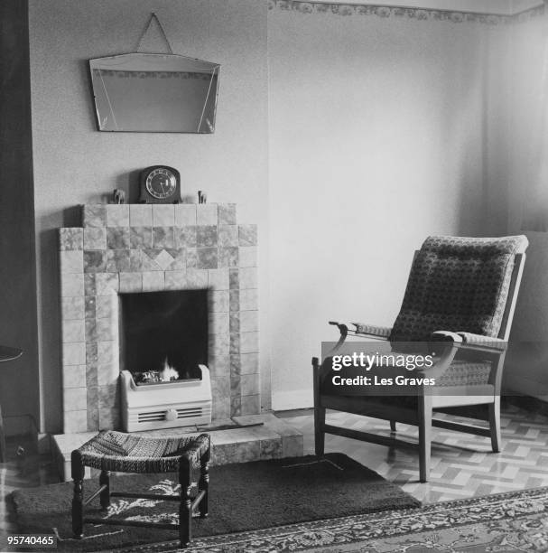 Fire burns in the grate next to an armchair, April 1953.