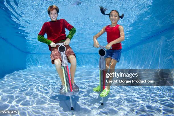 Girl and boy jumping on Pogo Stick underwater