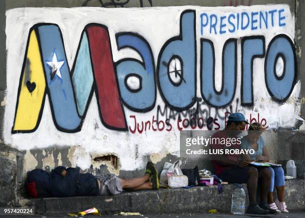 People stand next to a graffiti allusive to electoral advertising of Venezuelan President and reelection candidate Nicolas Maduro Caracas on May 11,...