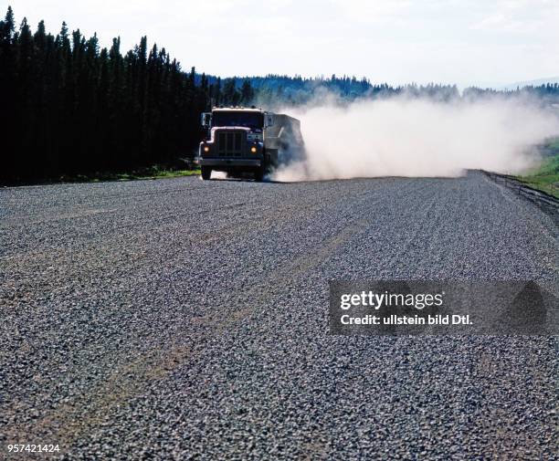 Fernlaster donnert in einer Wolke von Staub über den neuen Alaska Highway im Yukon