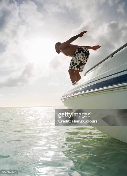 man diving into water from prow of boat - providenciales stock pictures, royalty-free photos & images
