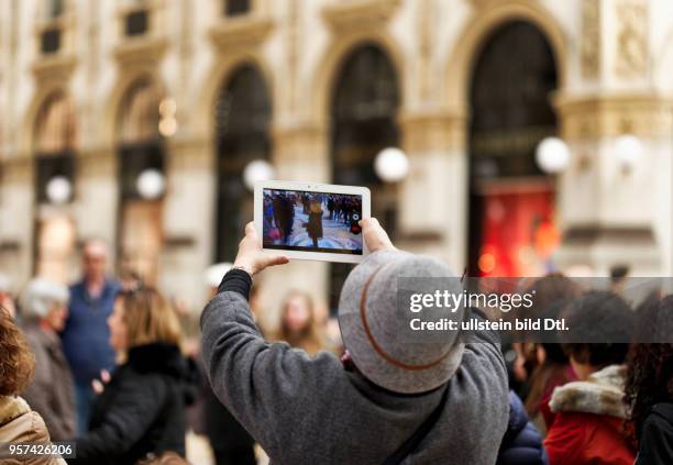 Tourist is taking pictures with her tablet computer in the shopping mall Galleria Vittorio Emanuele II in Milan ,