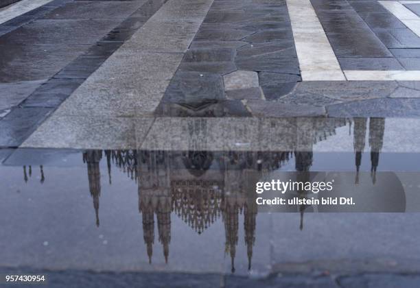 The cathedral Santa Mariae Nascenti in Milan is reflecting in a puddle on cathedral square ,