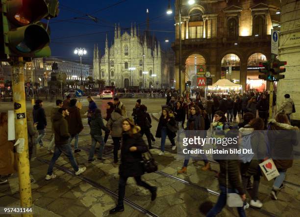 Pedestrians in Milan at nighttime with the cathedral Santa Mariae Nascenti in the background ,