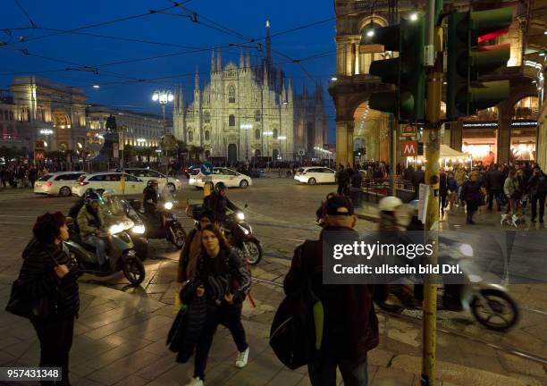 Pedestrians in Milan at nighttime with the cathedral Santa Mariae Nascenti in the background ,